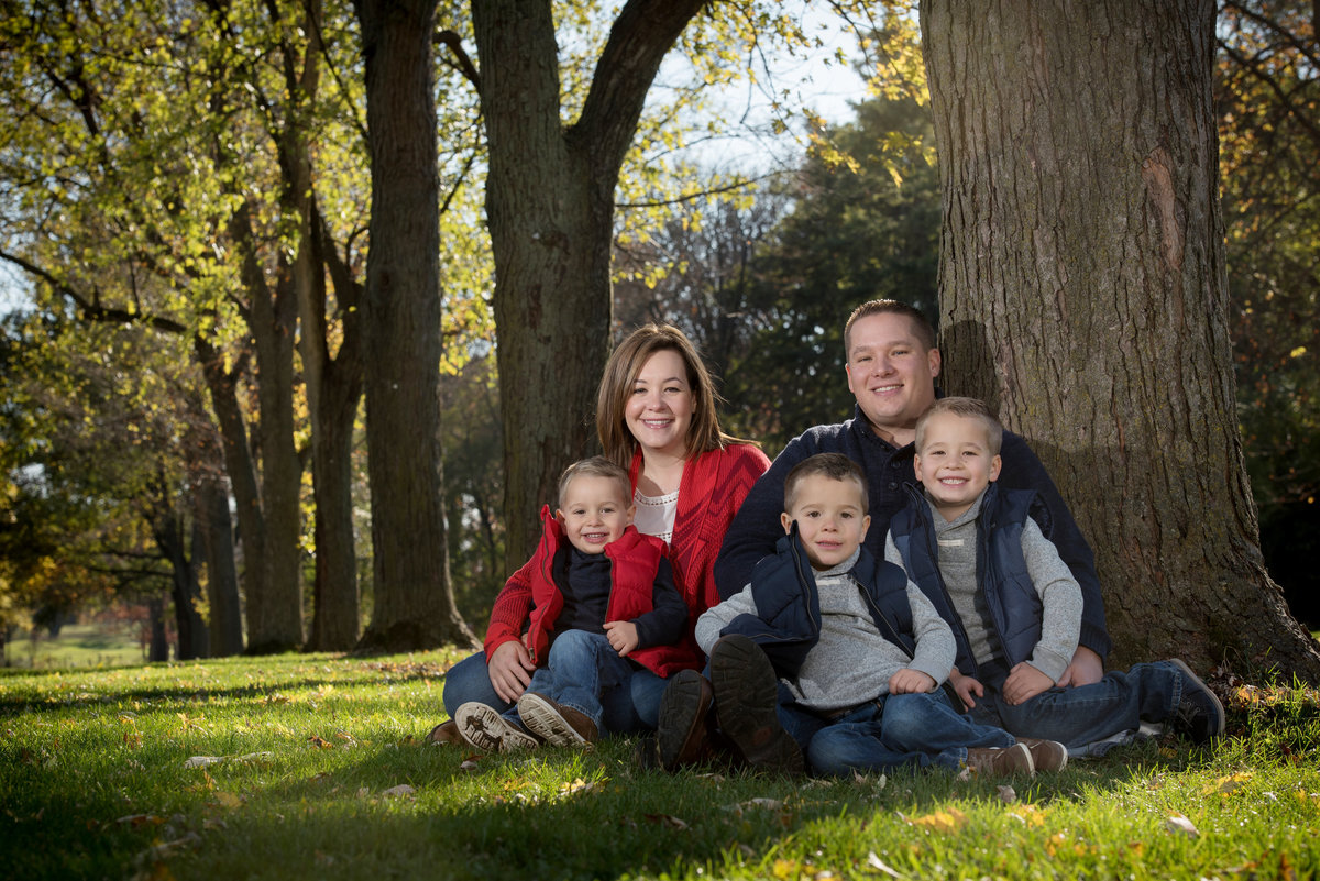 Family of five next to a row of large trees during an autumn family portrait
