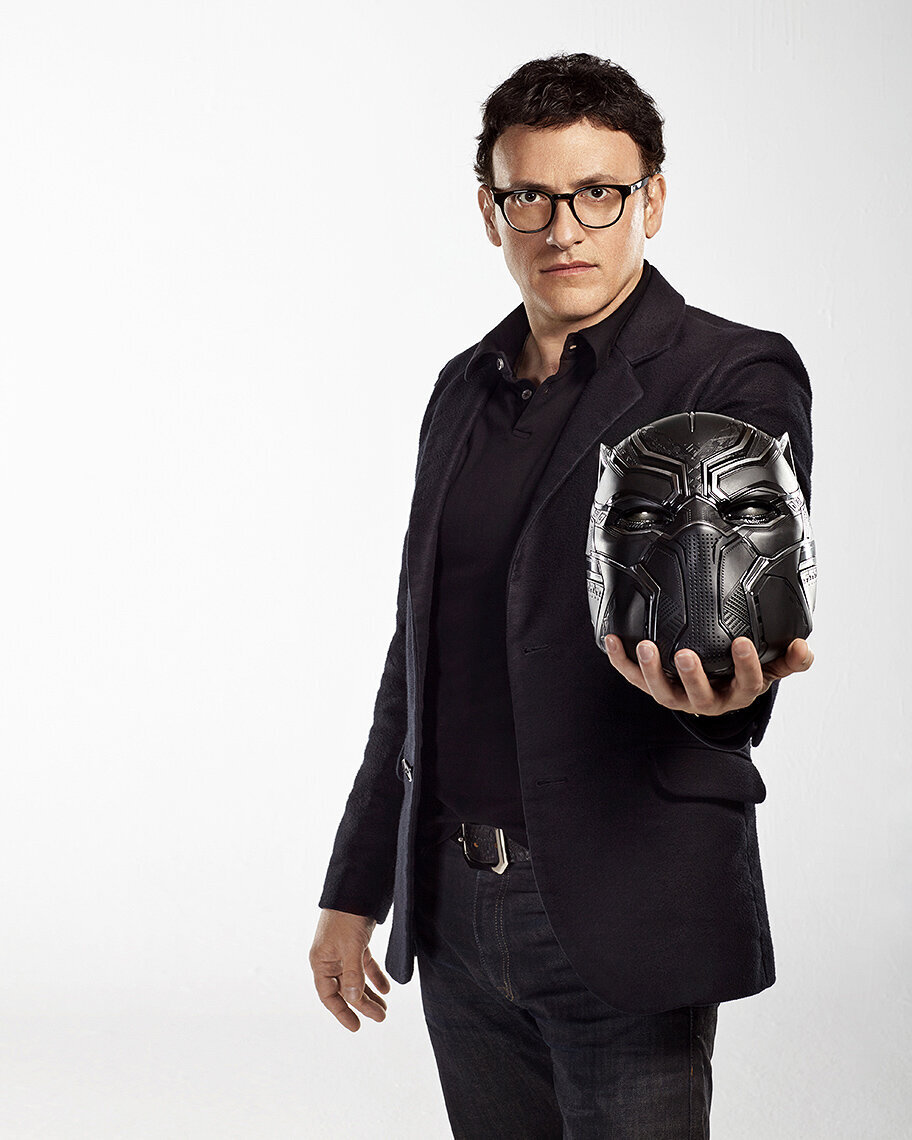 Portrait of Anthony Russo holding a black camera, wearing a dark suit, captured by Ylva Erevall.