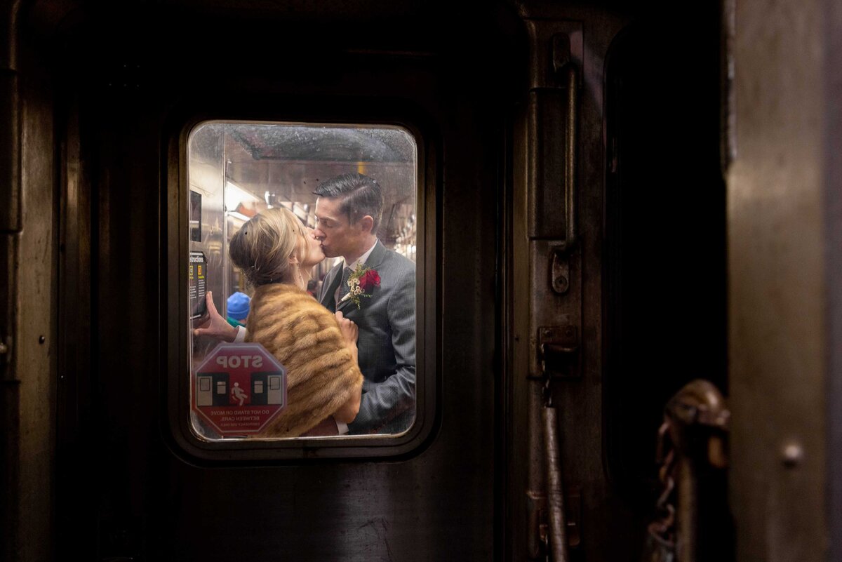 Image of a couple kissing through a small subway window.