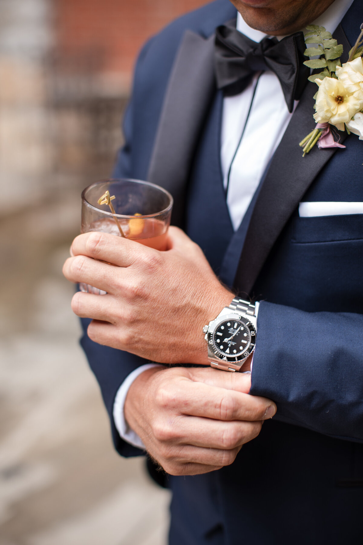 groom holding drink in navy suit