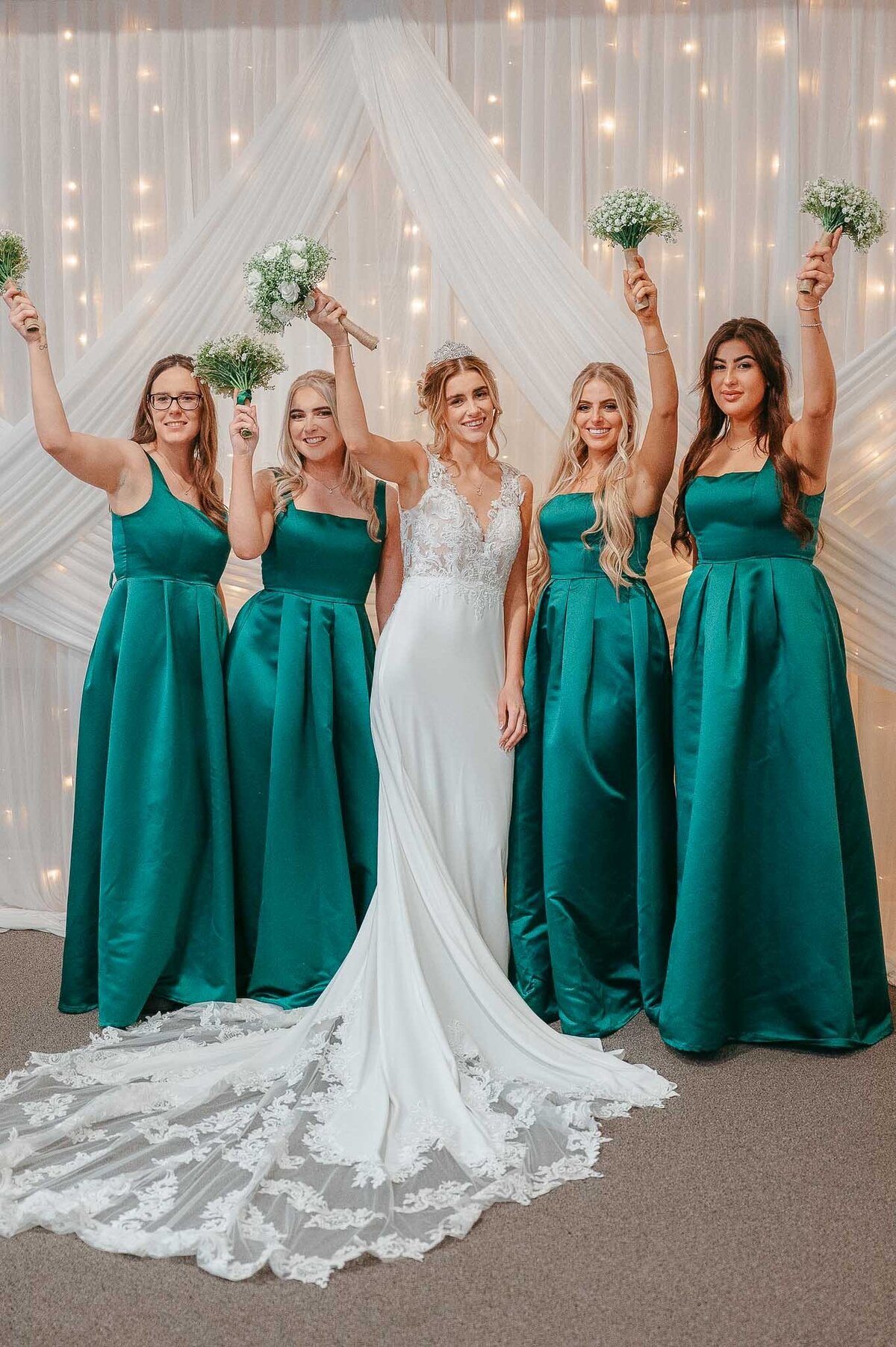 Bridesmaids in teal dresses celebrating at wedding reception in Cheshire with bride and their bouquet in Liverpool - Wedding Photographer