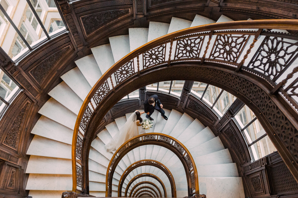 Newlyweds walk up the historic staircase at the Rookery in Chicago