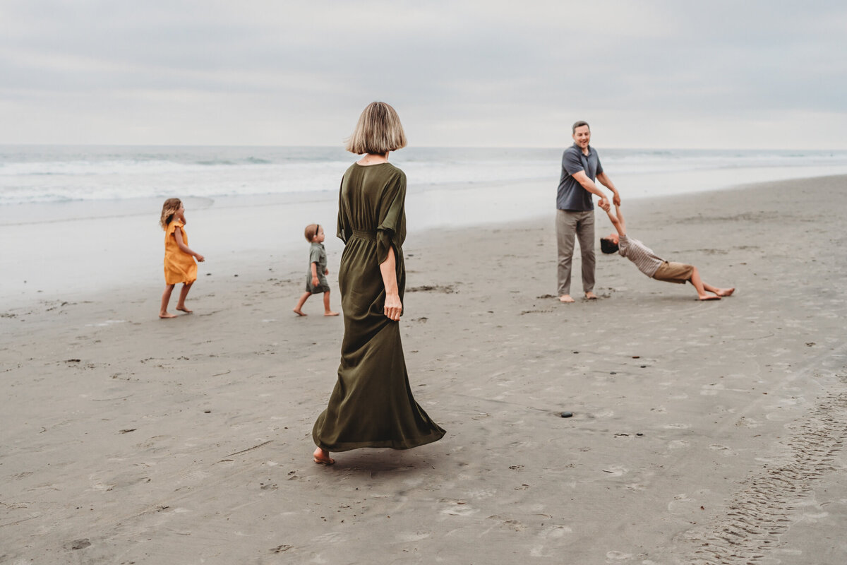 Family playing together on the sand at Del Mar beach during a San Diego family photography session.