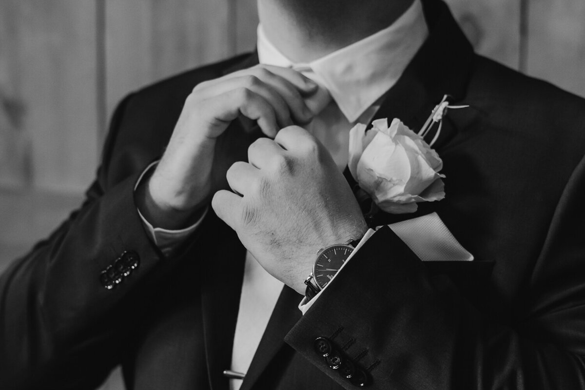 groom-tying-tie-black-and-white-wedding-detail-ashton-hill-farm-cedar-rapids-iowa-storyteller-collective-photo-co