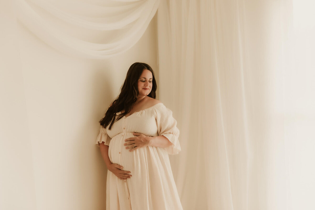 Maternity photo of a mother leaning agains a wall in a studio in OKC.