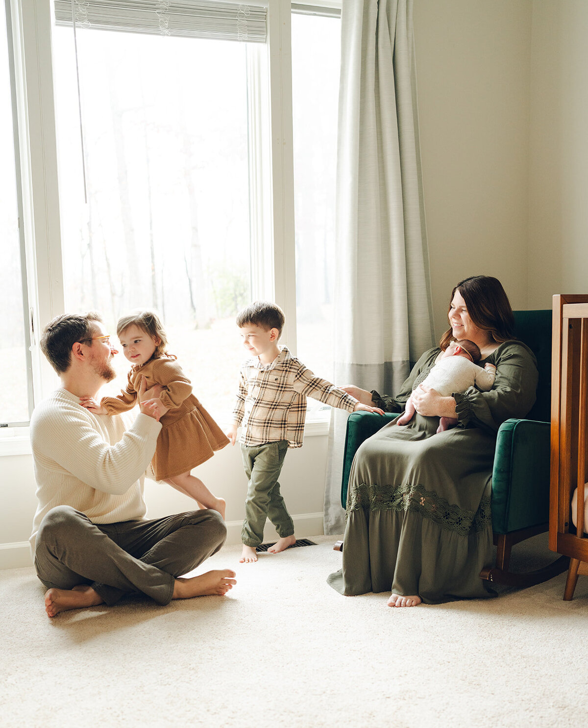 Parents and children playing together in the nursery during a relaxed, candid newborn session at home