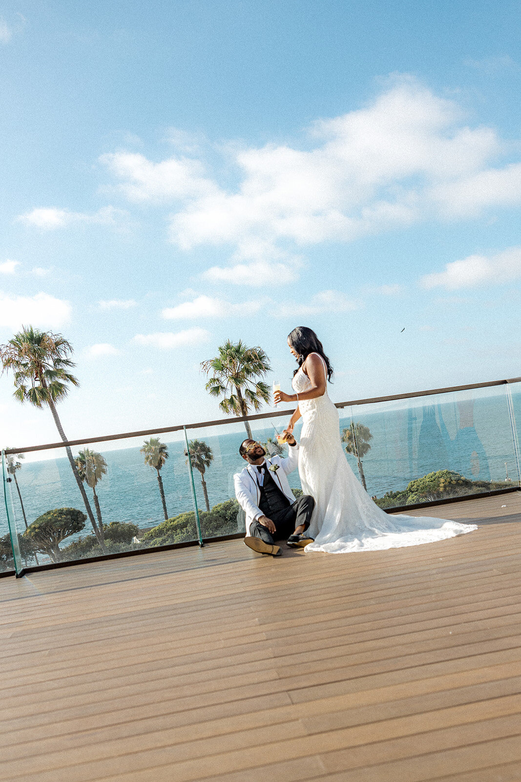 Groom looking up at bride on balcony in San Diego with ocean in the back