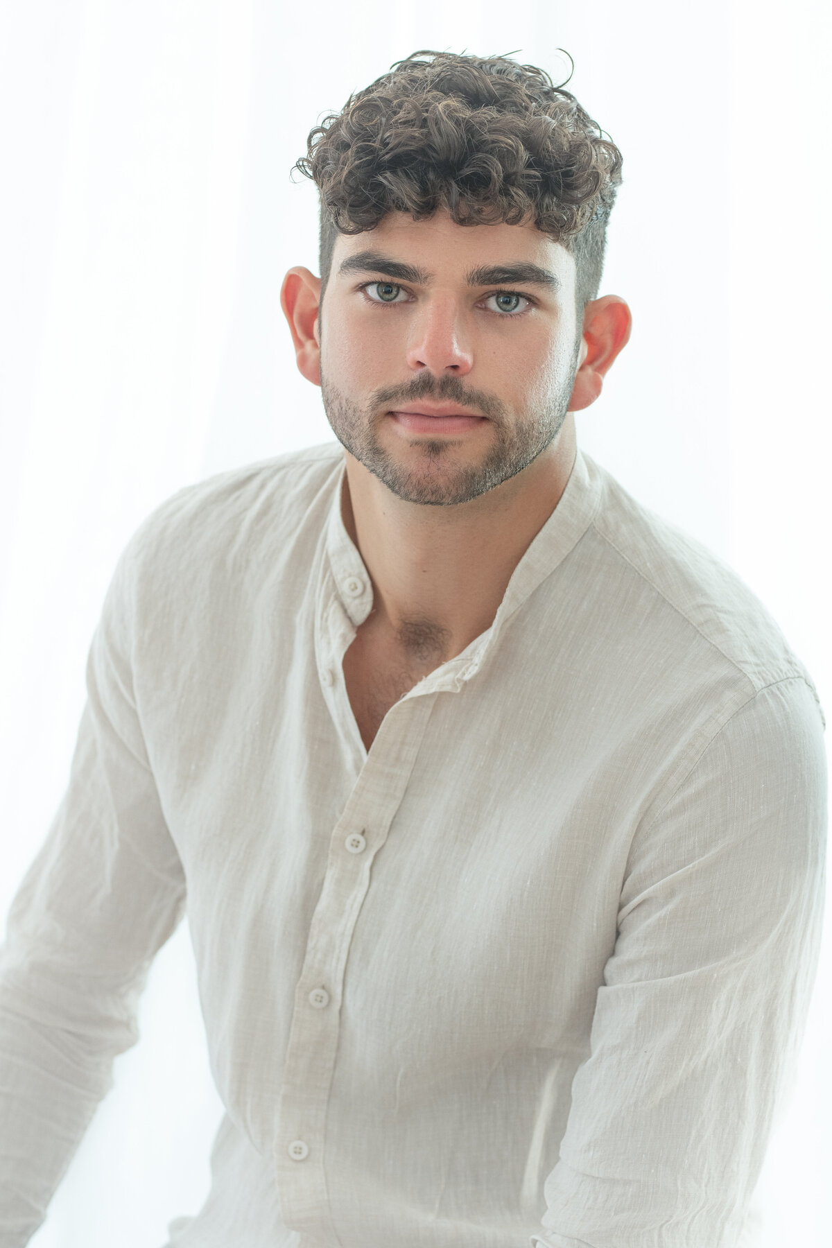 Studio Ace Photography Zaltbommel licht tijdloos portret van man met mooie donkere krullen en blauwe ogen