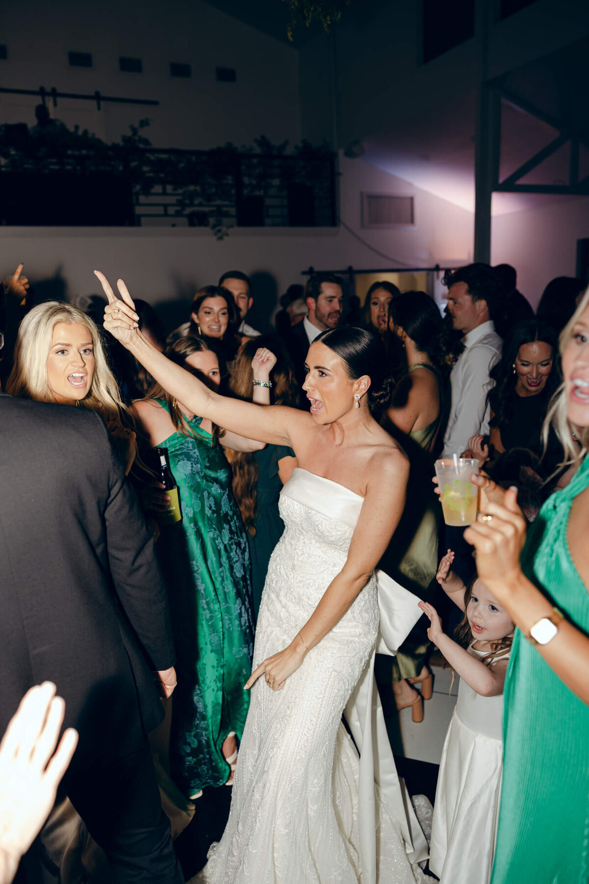 A candid wedding photo of the bride dancing at her wedding reception surronded by her wedding guests
