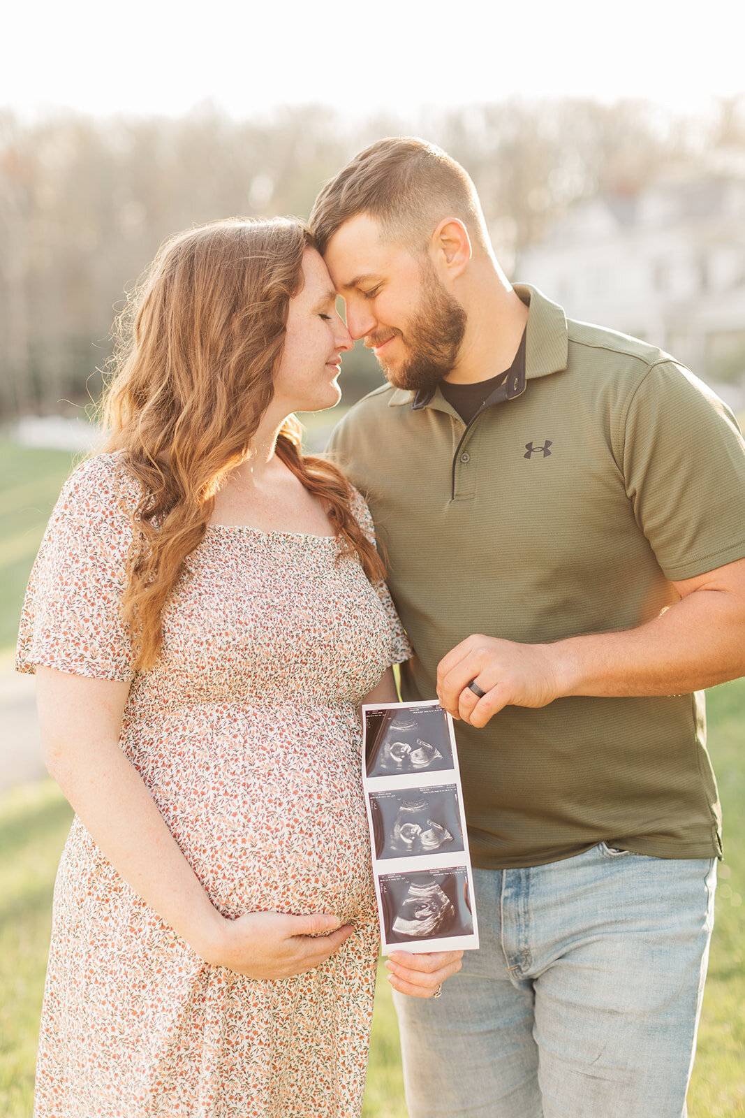 Couple soaking in the pregnancy  with ultrasound photos during maternity portrait session in Boone NC