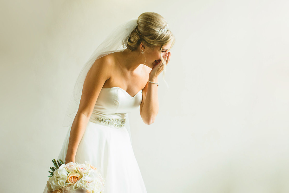 bride laughing white wall