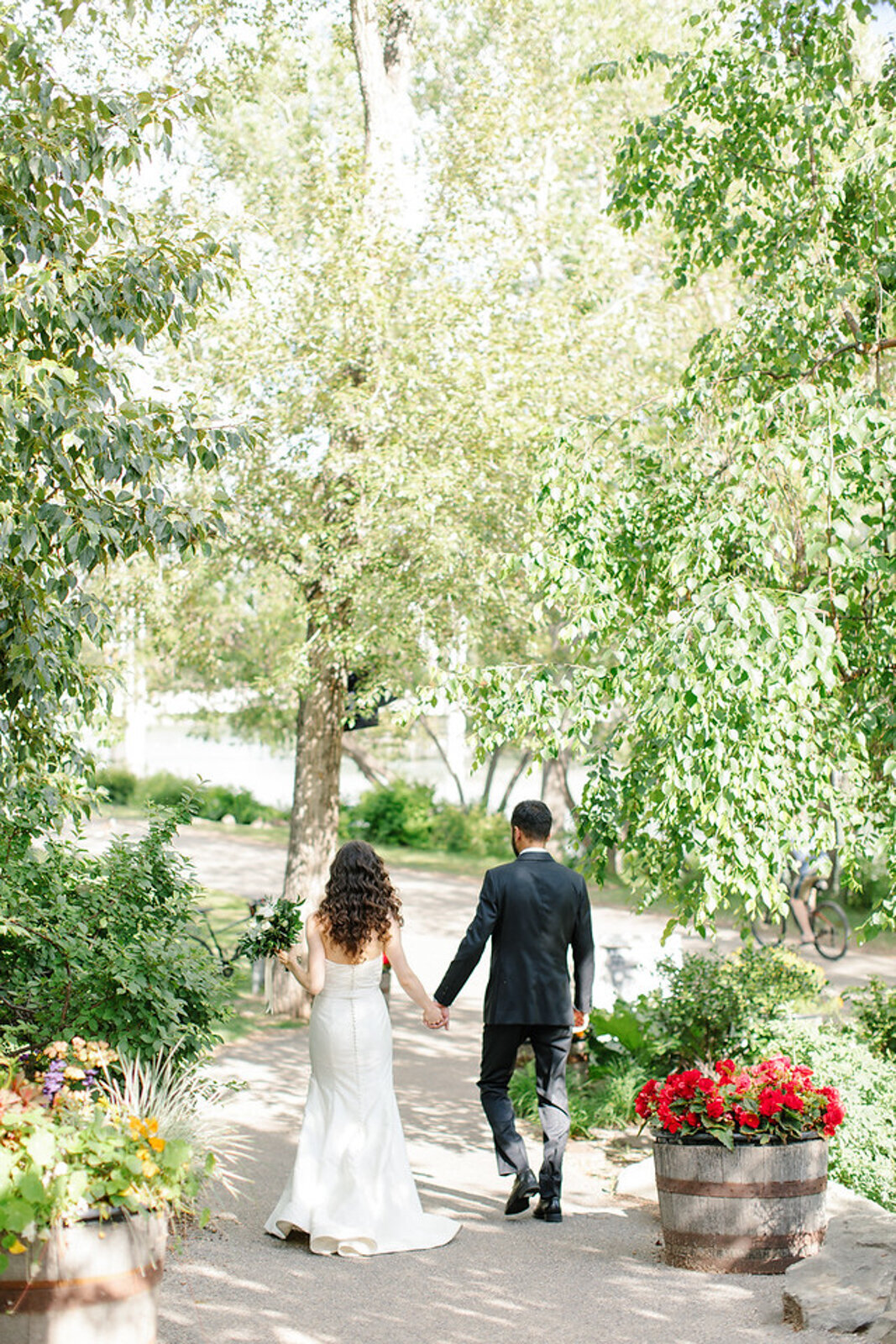 Couple walking holding hands at River Cafe, a riverside wedding venue in downtown Calgary, featured on the Brontë Bride Vendor Guide.