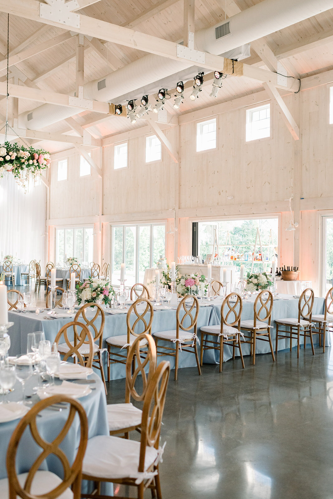 Details of a wedding reception set up with blue linen and wooden chairs