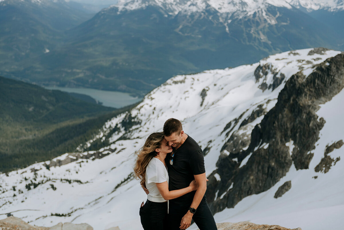 Couple cuddles on Rainbow Glacier in the summer after getting engaged