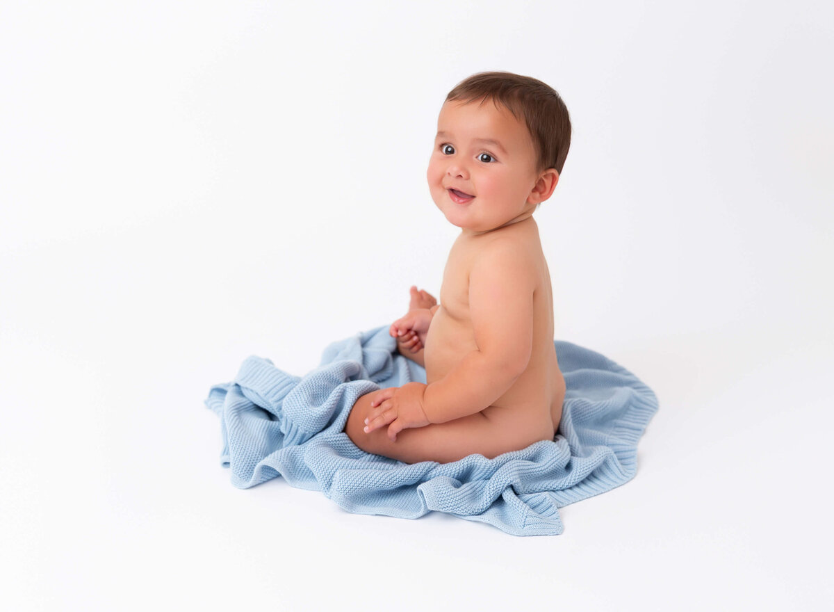 Modern baby photoshoot in Brooklyn 8 months old boy sitting on a blue blanket 