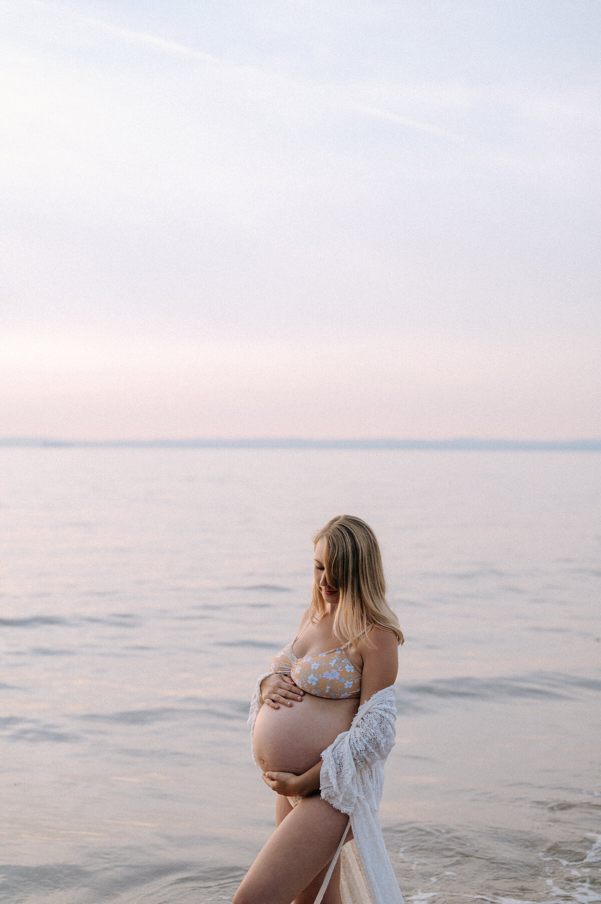 A pregnant woman stands in the sea during a maternity photoshoot near Bristol