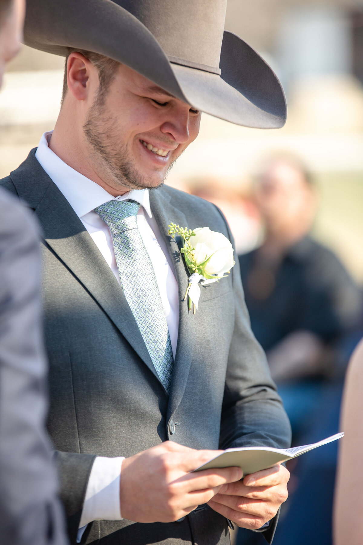 groom in gray cowboy hat reads vows at wedding alter in Boerne Texas