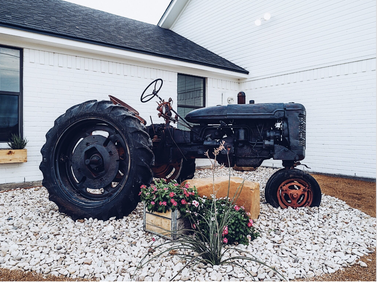 Vintage tractor decor in front of this three-bedroom, 2-bathroom vacation lake house for 10 guests with free wifi, dock access on private lake, fishing, bunk room, huge yard in close proximity to Magnolia, Baylor and downtown Waco, TX.