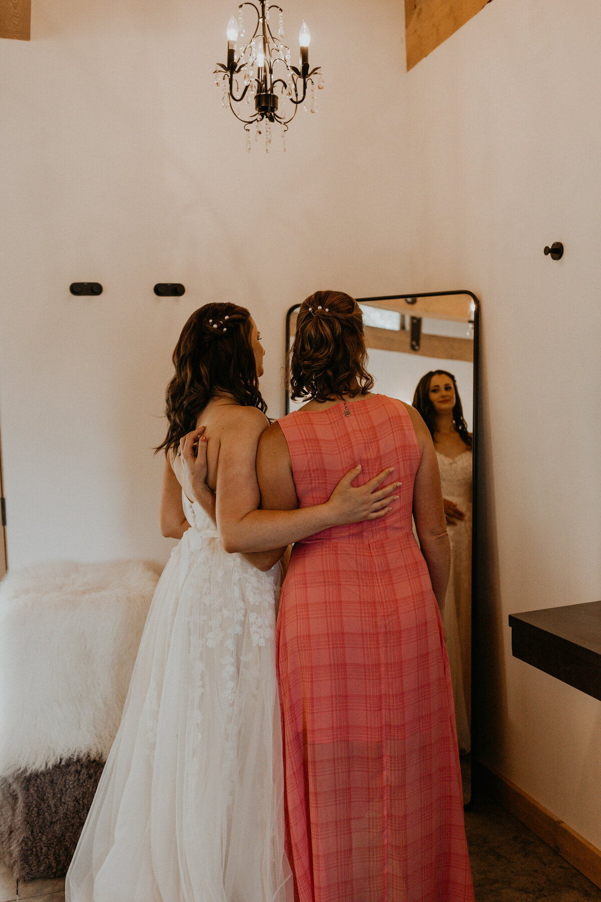 bride and her mom getting  in her wedding dress