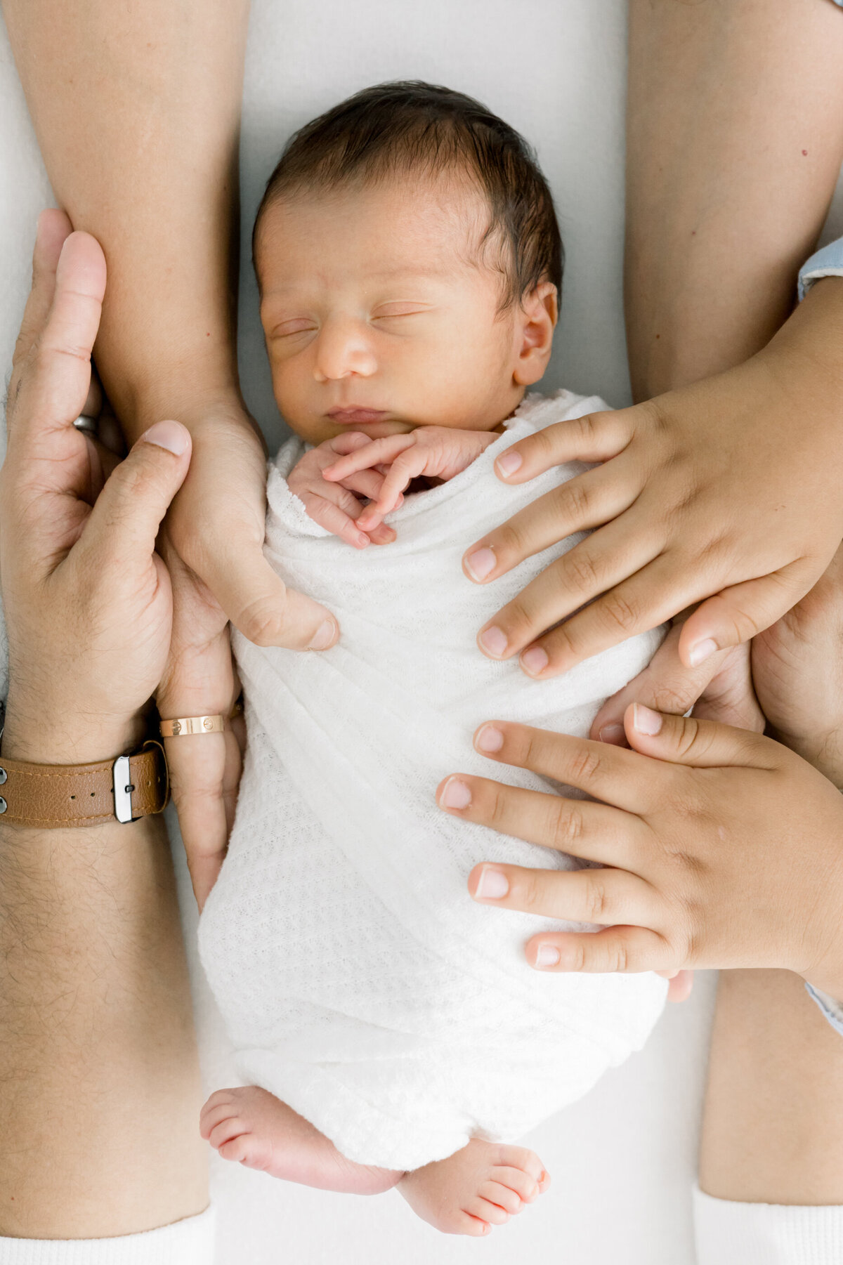 close up of parents' hands on a newborn baby