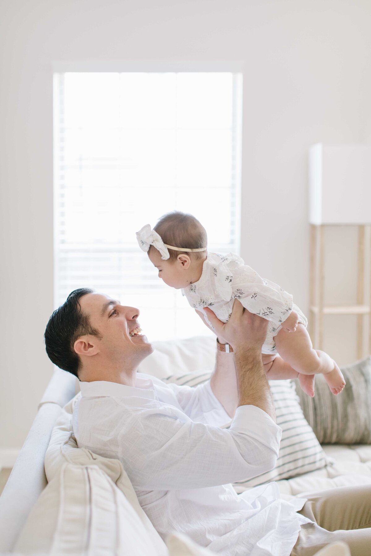 father holding up baby girl and smiling at her