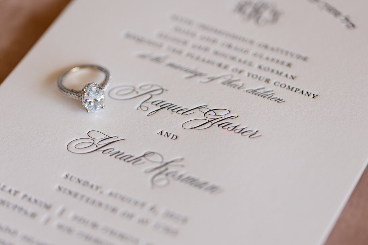 An engagement ring on top of a wedding invitation