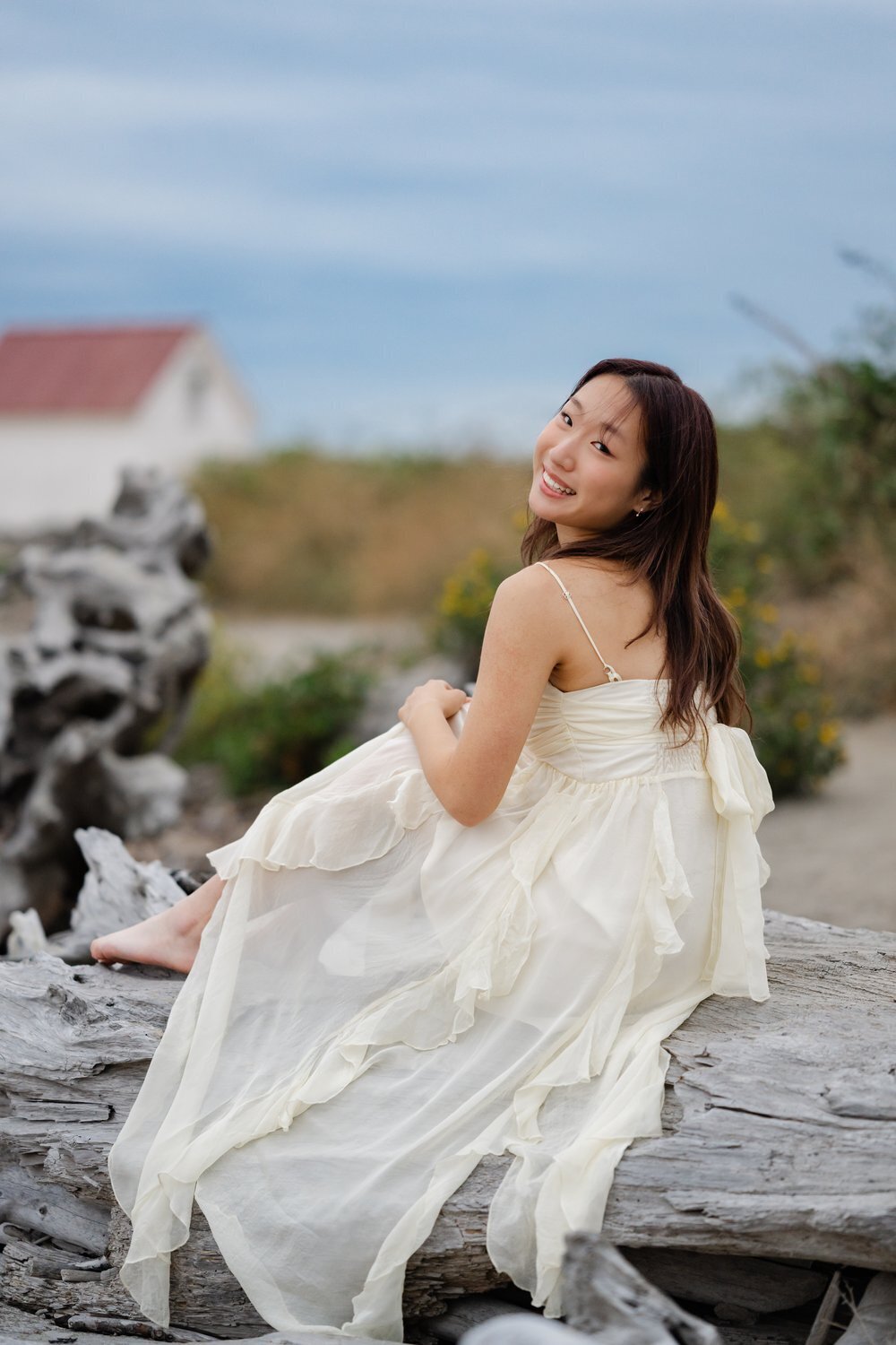 lighthouse senior girl sitting on driftwood