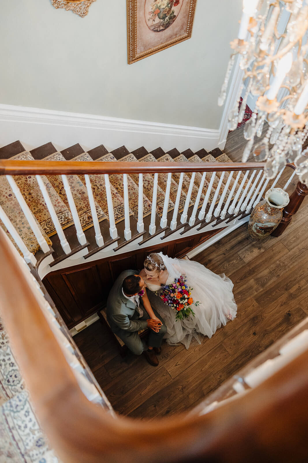 Looking down the stairs at bride and groom sitting on bench at The Mansion at Keuka Lake, NY
