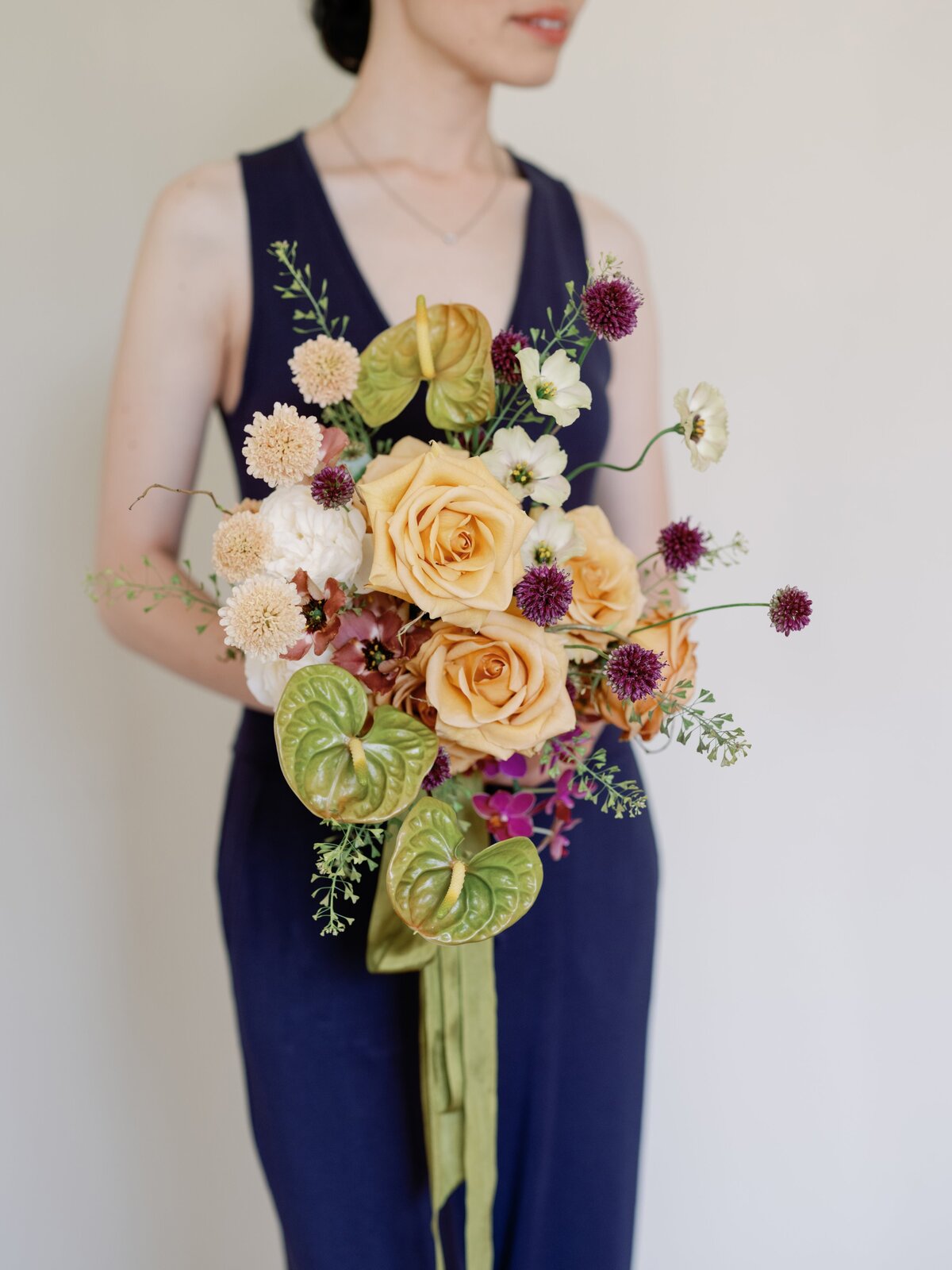 modern bridal bouquet with anthuriums and alliums lisianthus held by a florist for a san francisco elopement