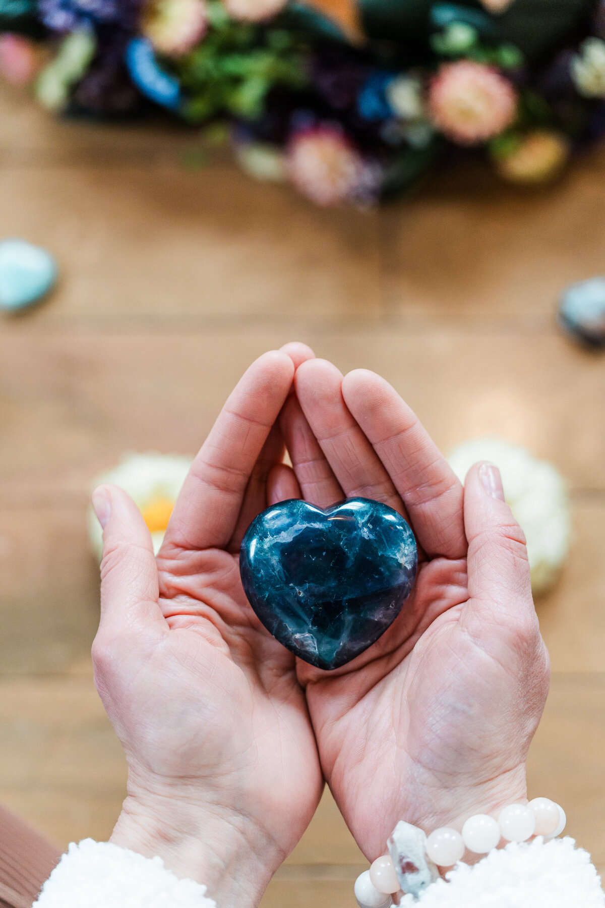 a woman holds a heart shaped Flourite crystal in her open hands