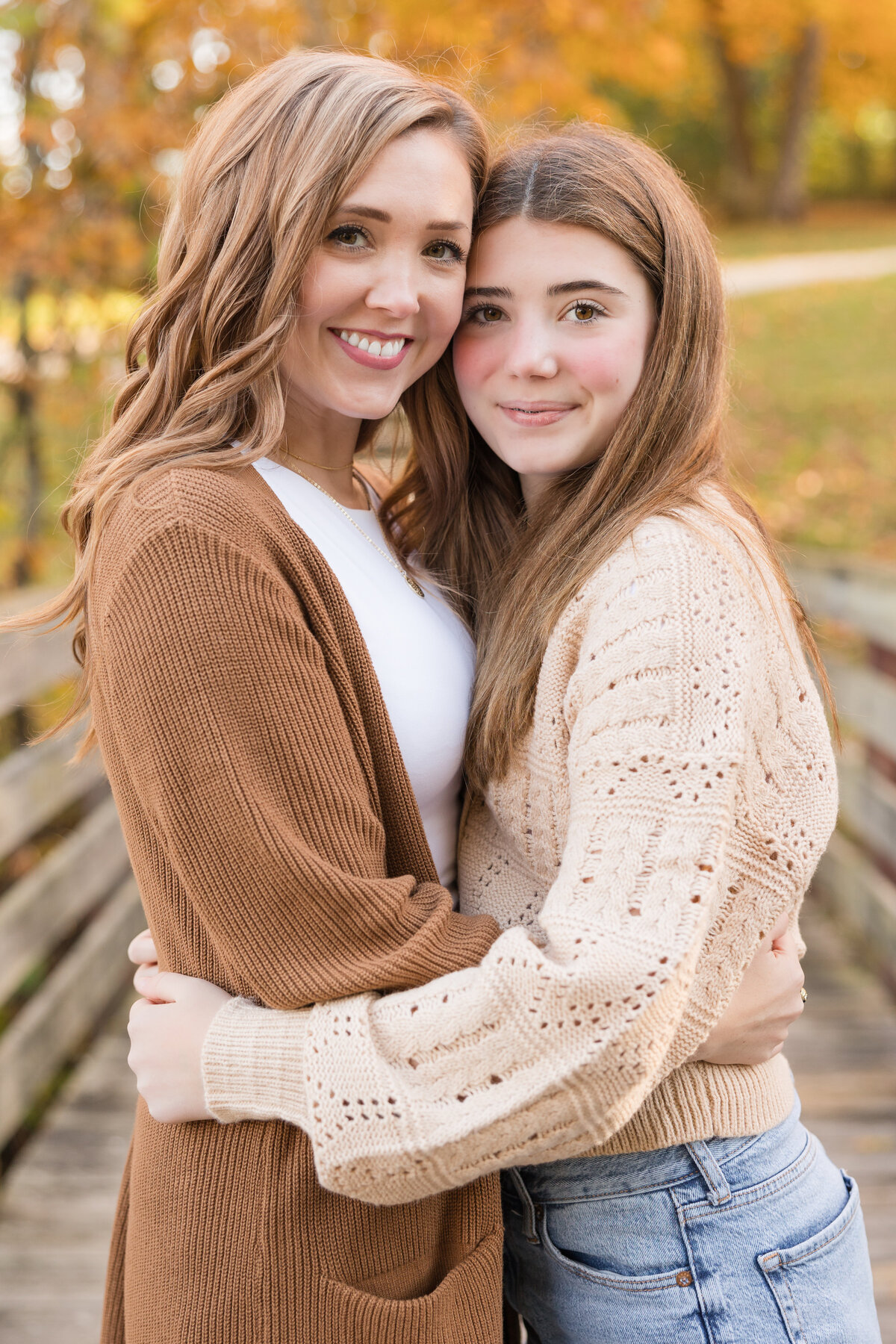 A mother and her daughter are hugging and smiling at the camera