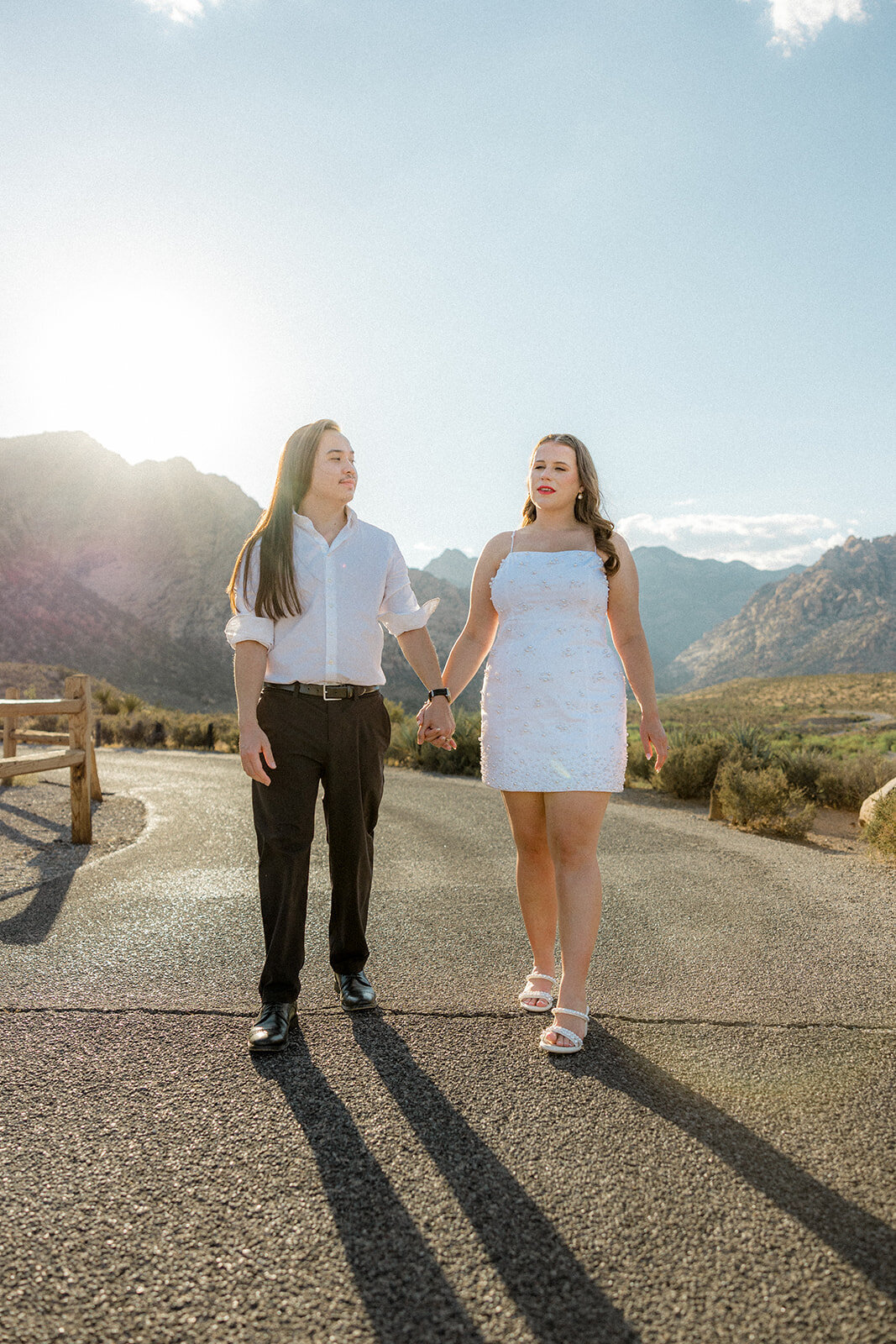 Engaged couple walking on empty road with Nevada mountains in the back