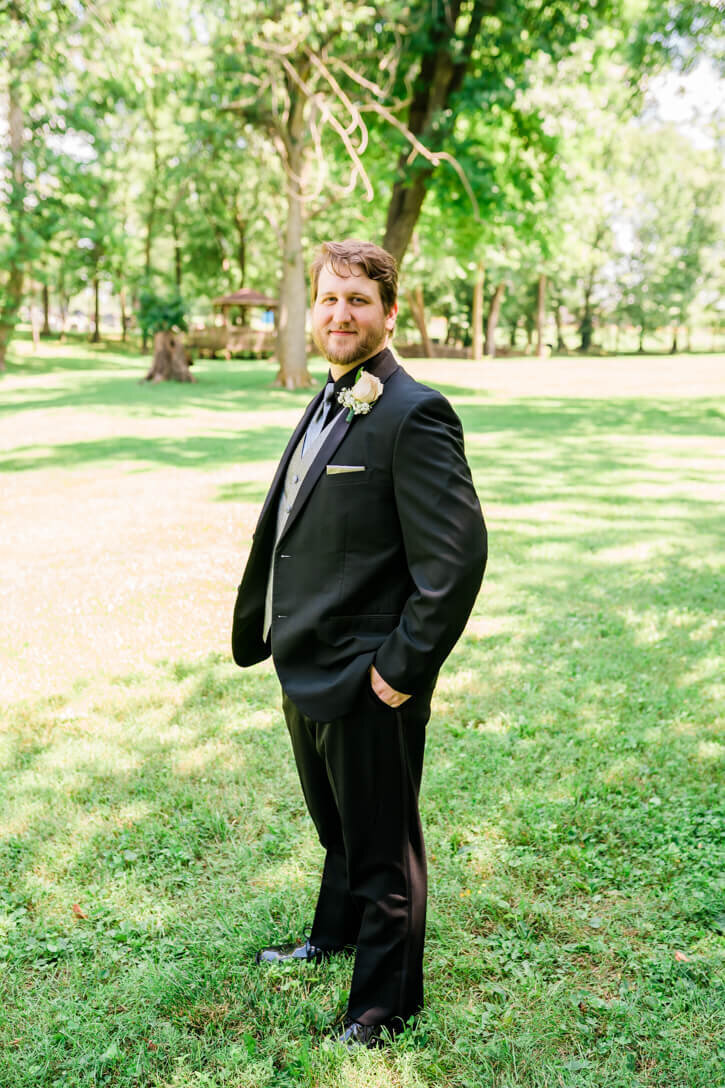 Outdoor groom portrait on his wedding day smiling with his hands in his pockets.