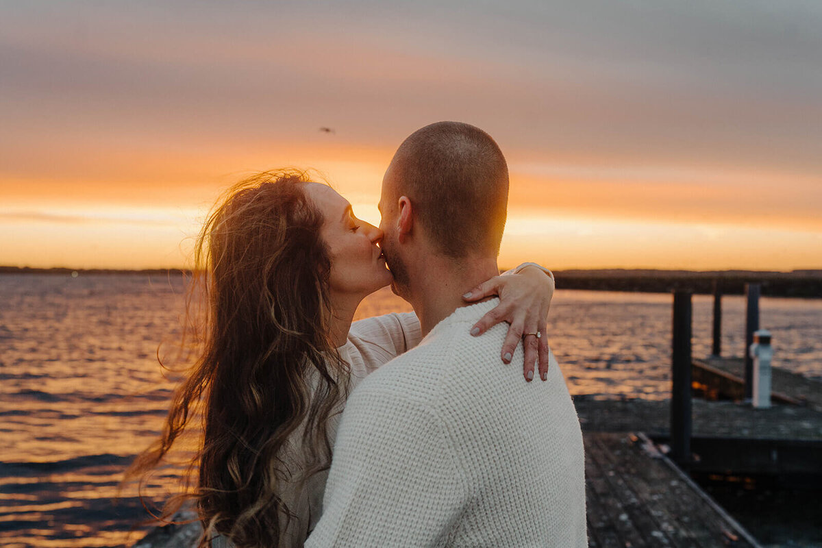 Couple kissing overlooking lake at sunset at Finger Lakes engagement session