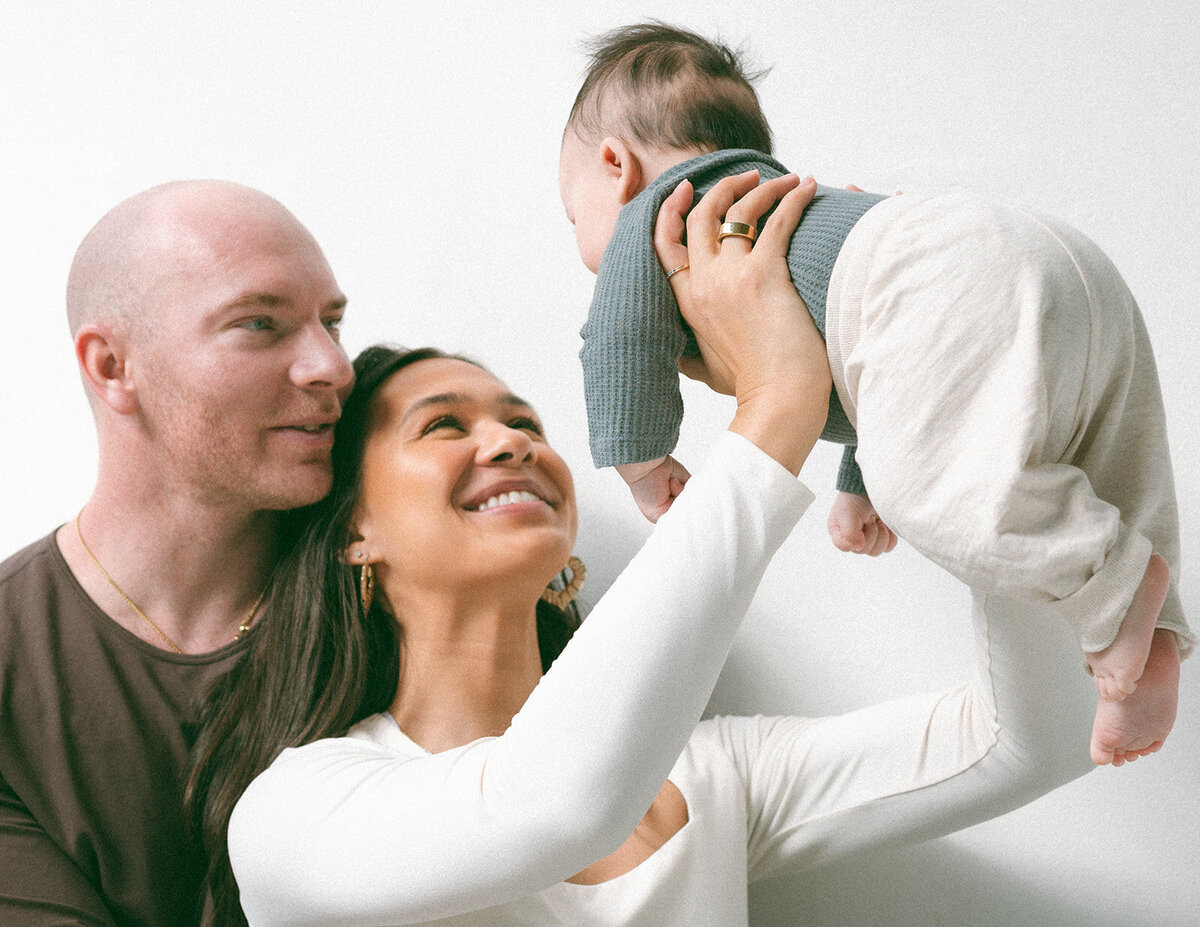 Parents lifting baby together during relaxed newborn family session in Orange County.