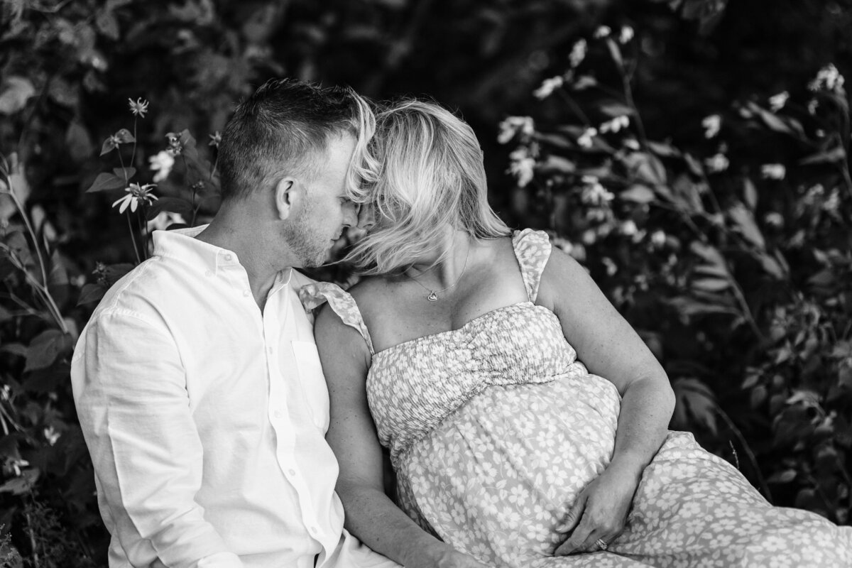 A black and white photo of the couple sitting closely together, with their foreheads touching.