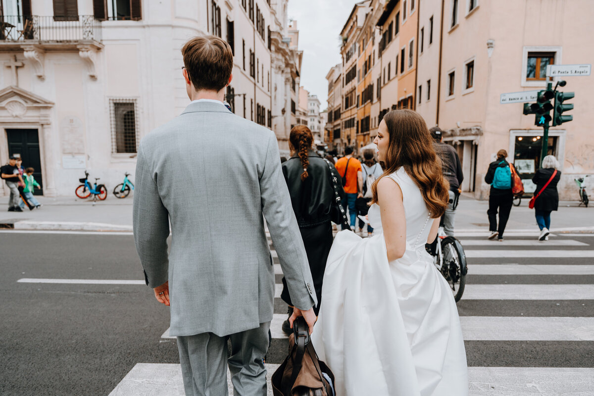 Couple walking across a Roman street holding hands.
