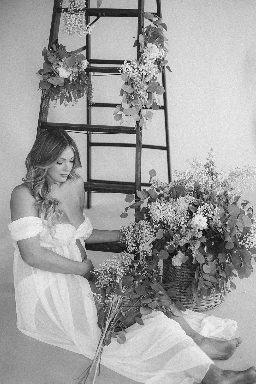 A pregnant woman poses surrounded by flowers