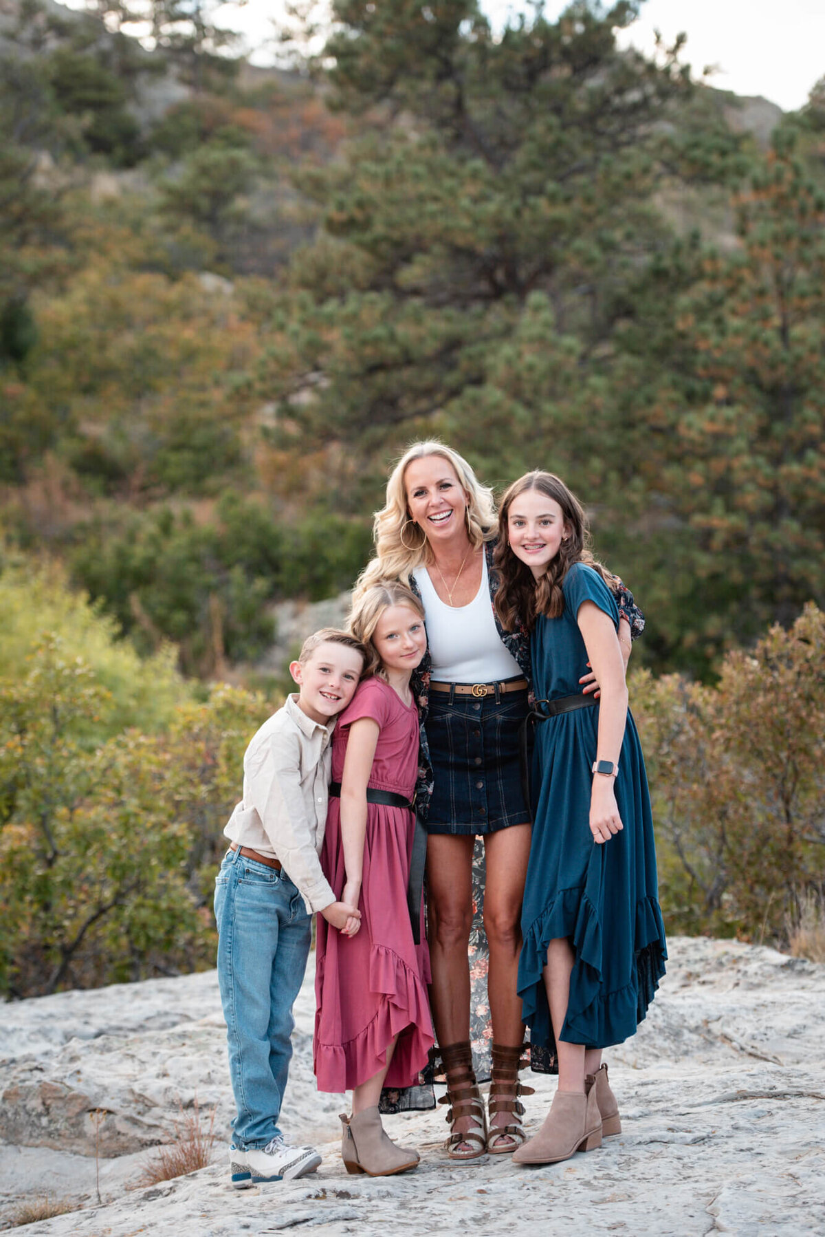 A mother laughs and hugs her three children standing on a trail