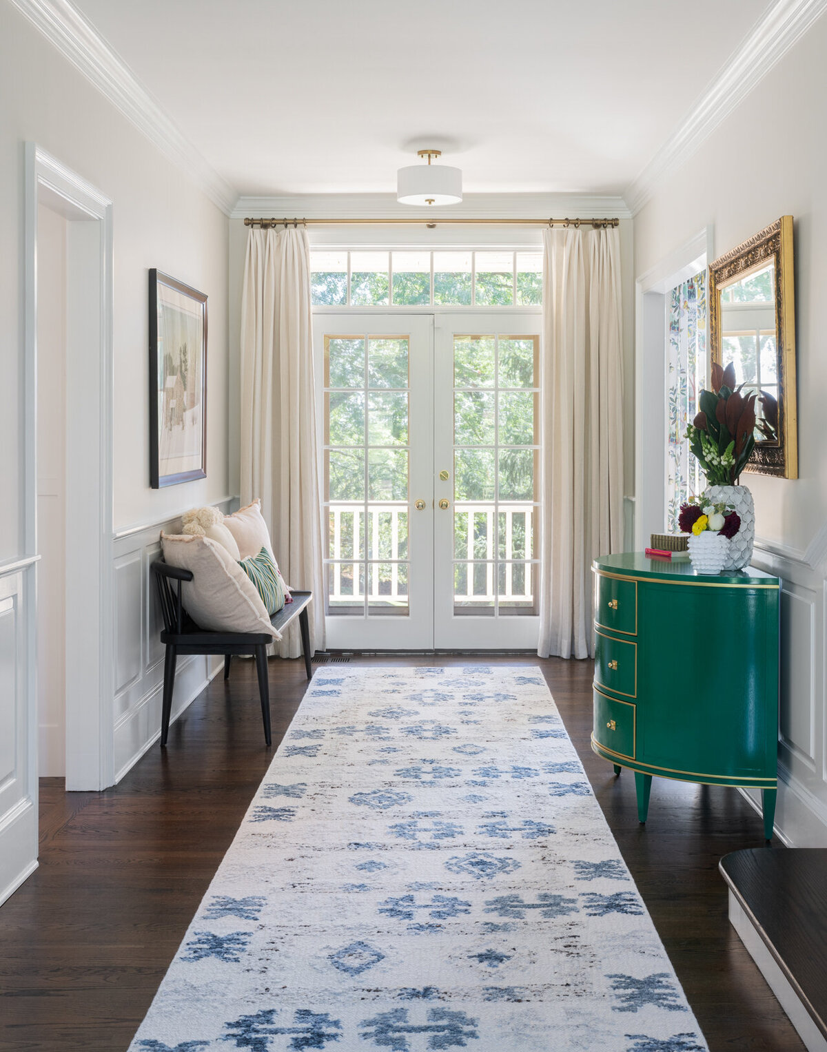 bright entryway with white and blue patterned runner rug and white French doors