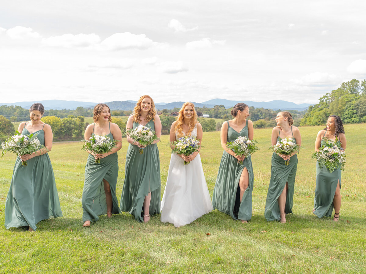 The bride and bridesmaids smiling while walking with the mountains at Renback barn in the background!