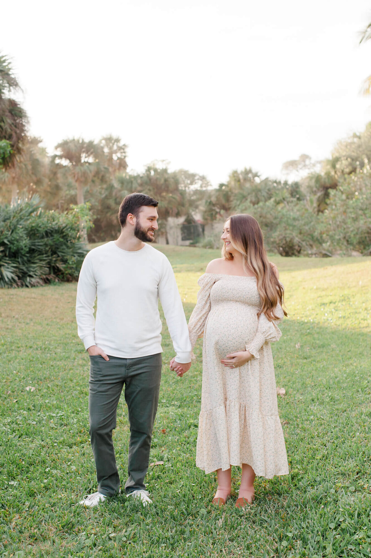 Pregnant couple holding hands and smiling at each other