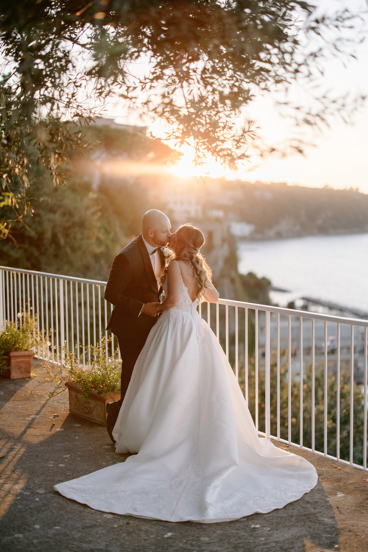 bride and groom kissing overlooking the sea at golden hour