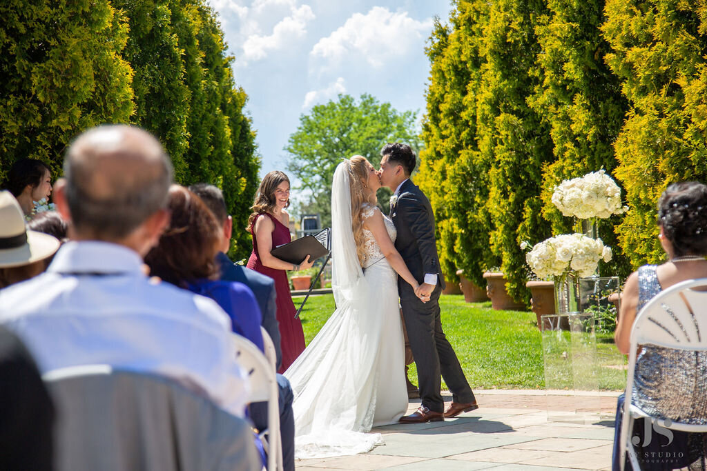 Bride and groom share a kiss during their wedding ceremony  at the Denver Botanic Gardens.