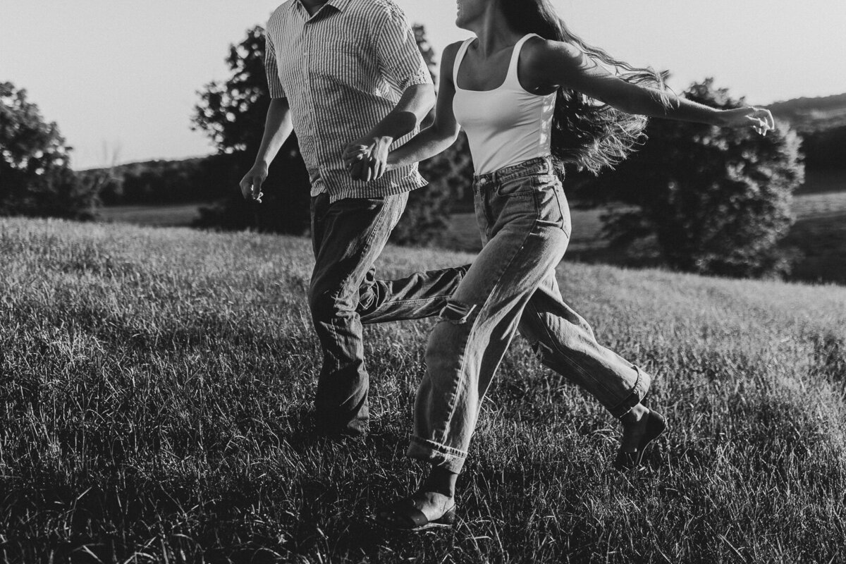 Midwest couple running together in a grassy field