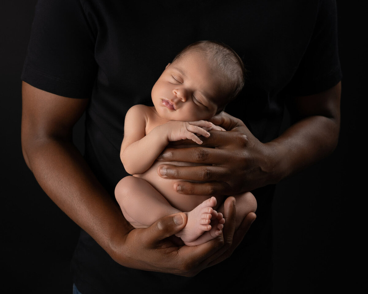 dad holding newborn baby in his hands during newborn session in Austin, Texas