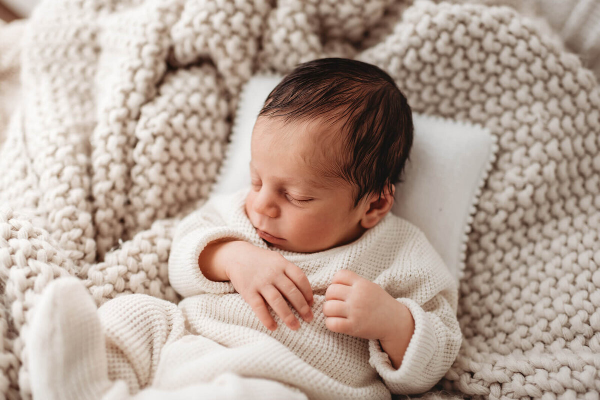 denver newborn baby in cozy outfit with his head on a baby pillow