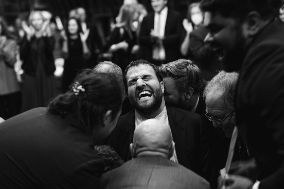 groom laughs as friends lift him in a chair