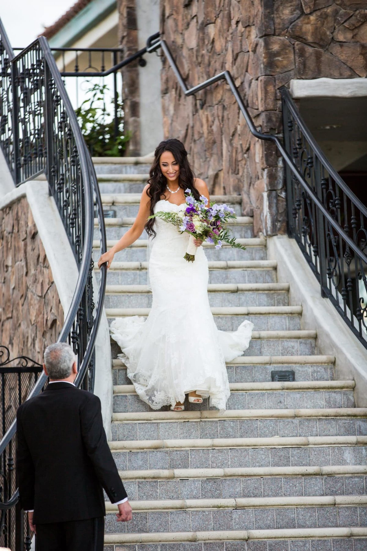 Bride walks down an outdoor staircase to her waiting father