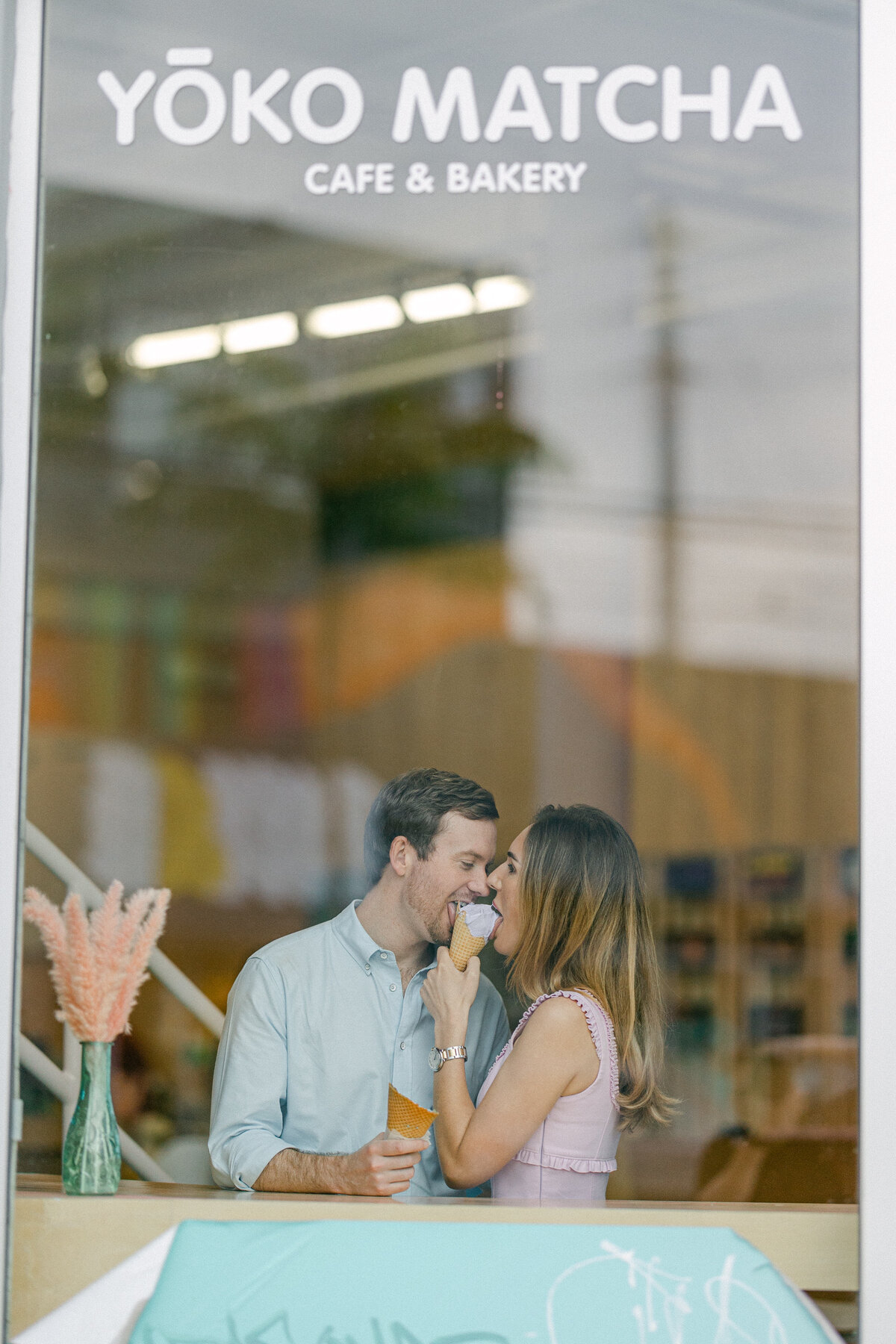 Engaged couple sharing ice cream together at Yoko Matcha Cafe & Bakery, capturing a sweet and intimate moment through the window, photographed by Rodrigo Varela Photography.